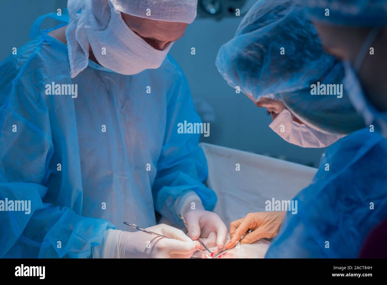Chirurgen Kinder urologische Operationen durchführen. Ein Mann und eine Frau in einer Maske und einem blauen sterile Mantel in den Operationssaal. Ein Team von Chirurgen ist Co Stockfoto