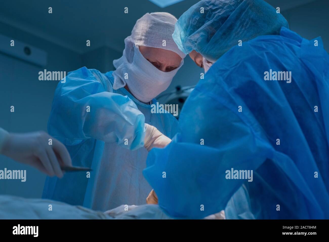 Chirurgen Kinder urologische Operationen durchführen. Ein Mann und eine Frau in einer Maske und einem blauen sterile Mantel in den Operationssaal. Ein Team von Chirurgen ist Co Stockfoto