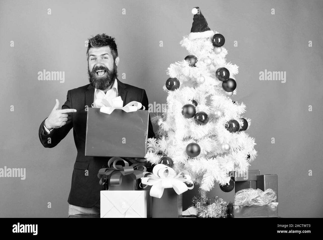 Bereit zu feiern. Weihnachten Vorbereitung und Feier. Weihnachten Geschenke und Dekorationen. Wie ehrfürchtig office Christmas Party organisieren. Man bärtige Hipster tragen Anzug in der Nähe der Weihnachtsbaum. Stockfoto