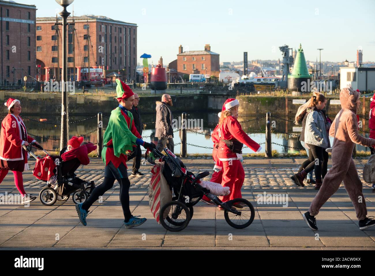 Wettbewerber in einem Elf Kostüm Schieben eines Kinderwagens an der Albert Dock, wie sie sich vorbereiten, an der 2019 Santa Strich in Liverpool UK zu übernehmen. Stockfoto