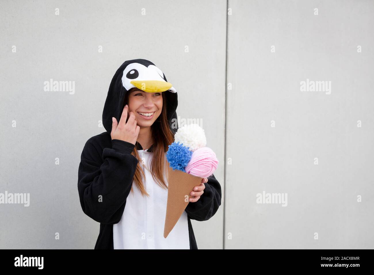 Schöne, junge Frau in Pinguin Kostüm ist Essen deco Eis in der Betonwand  Stockfotografie - Alamy