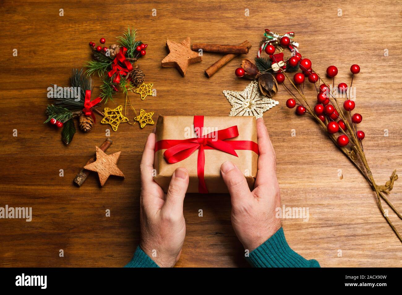 Ein Mann hält ein Weihnachtsgeschenk an einem hölzernen Tisch Stockfoto