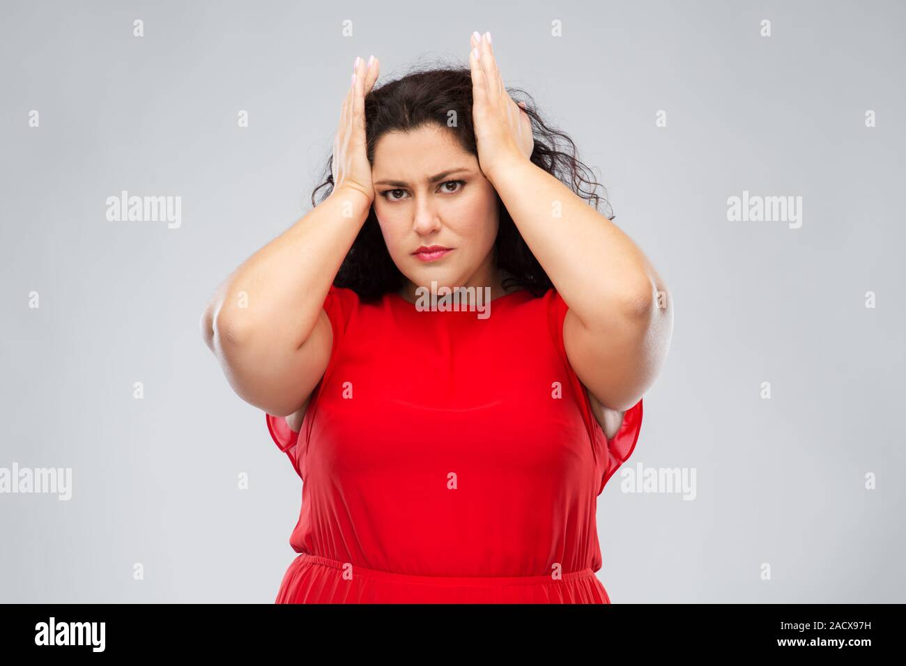 Menschen und Portrait Konzept - die Frau im roten Kleid leiden unter Kopfschmerzen über grauer Hintergrund Stockfoto