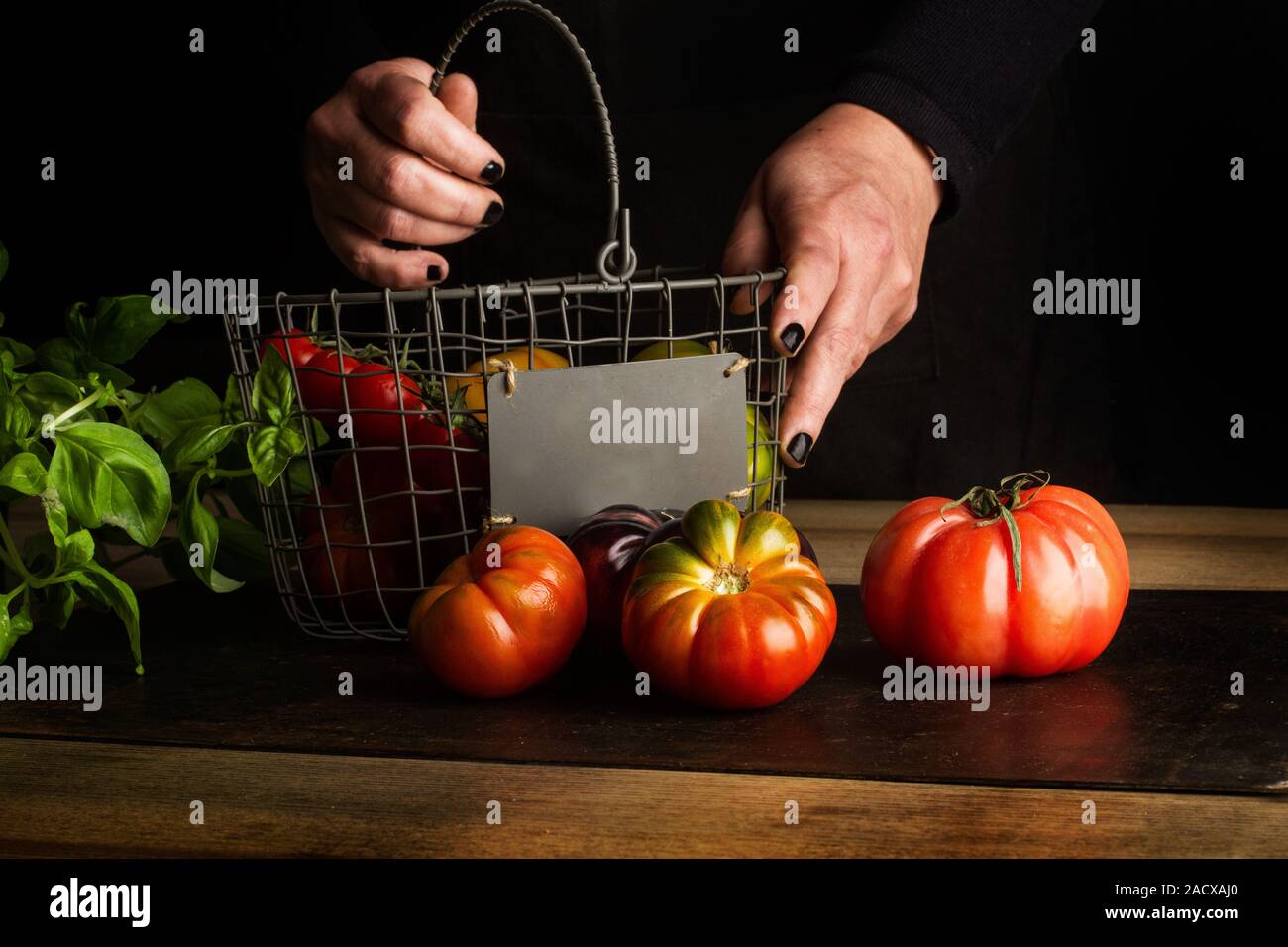 Frau setzen verschiedene Tomaten in einem Drahtkorb Stockfoto