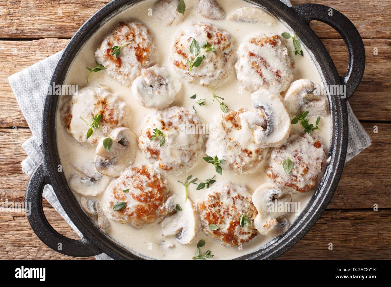 Hausgemachte Frikadellen mit Champignons in eine cremige Soße mit Thymian closeup in einer Pfanne auf dem Tisch gekocht. Horizontal oben Ansicht von oben Stockfoto