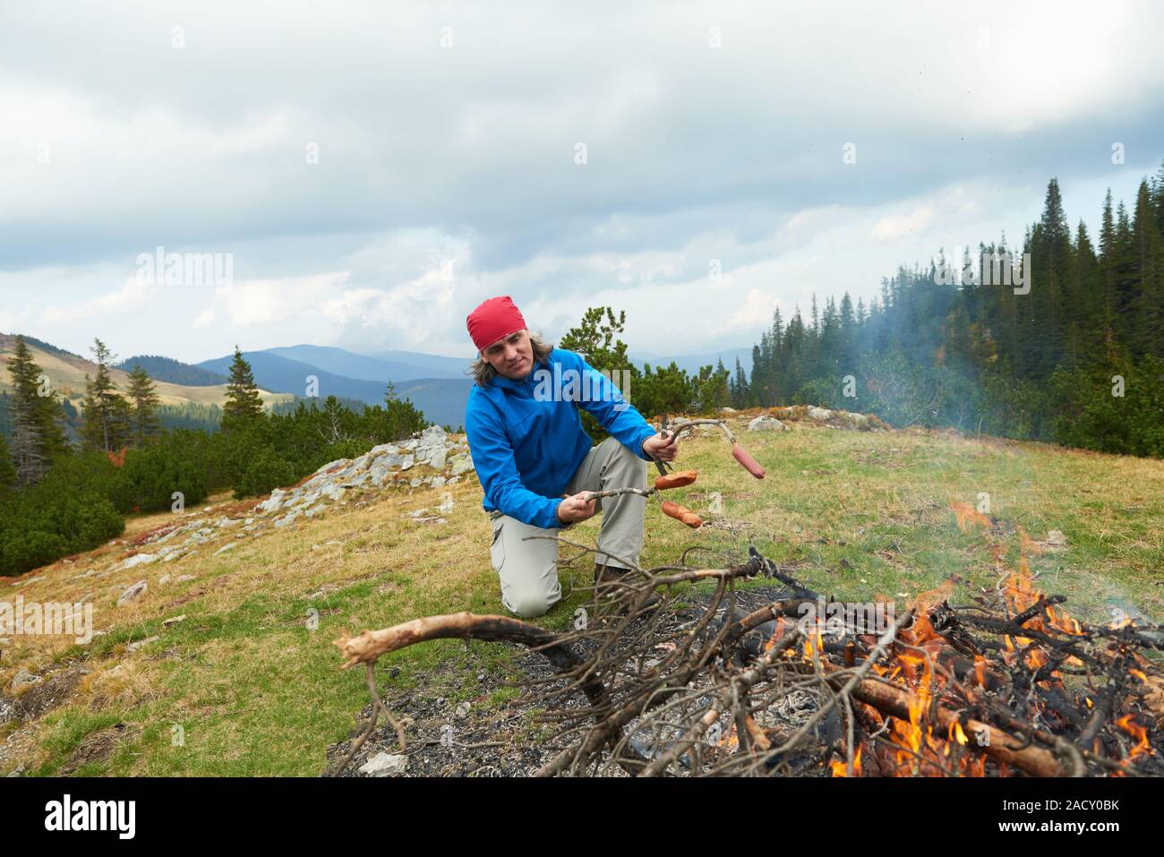 Wandern Menschen bereiten leckere Würstchen am Lagerfeuer Stockfoto