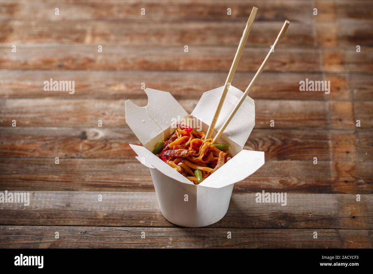 Nudeln mit Schweinefleisch und Gemüse in Take-out Box auf Holztisch Stockfoto