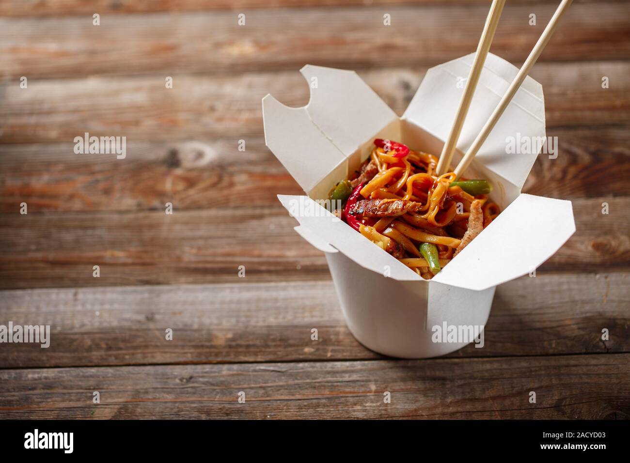 Nudeln mit Schweinefleisch und Gemüse in Take-out Box auf Holztisch Stockfoto