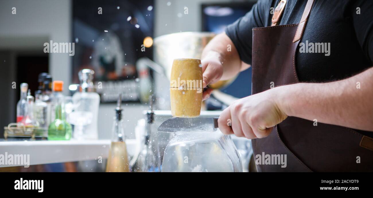 Barkeeper bricht Eis mit Holzhammer Stockfoto