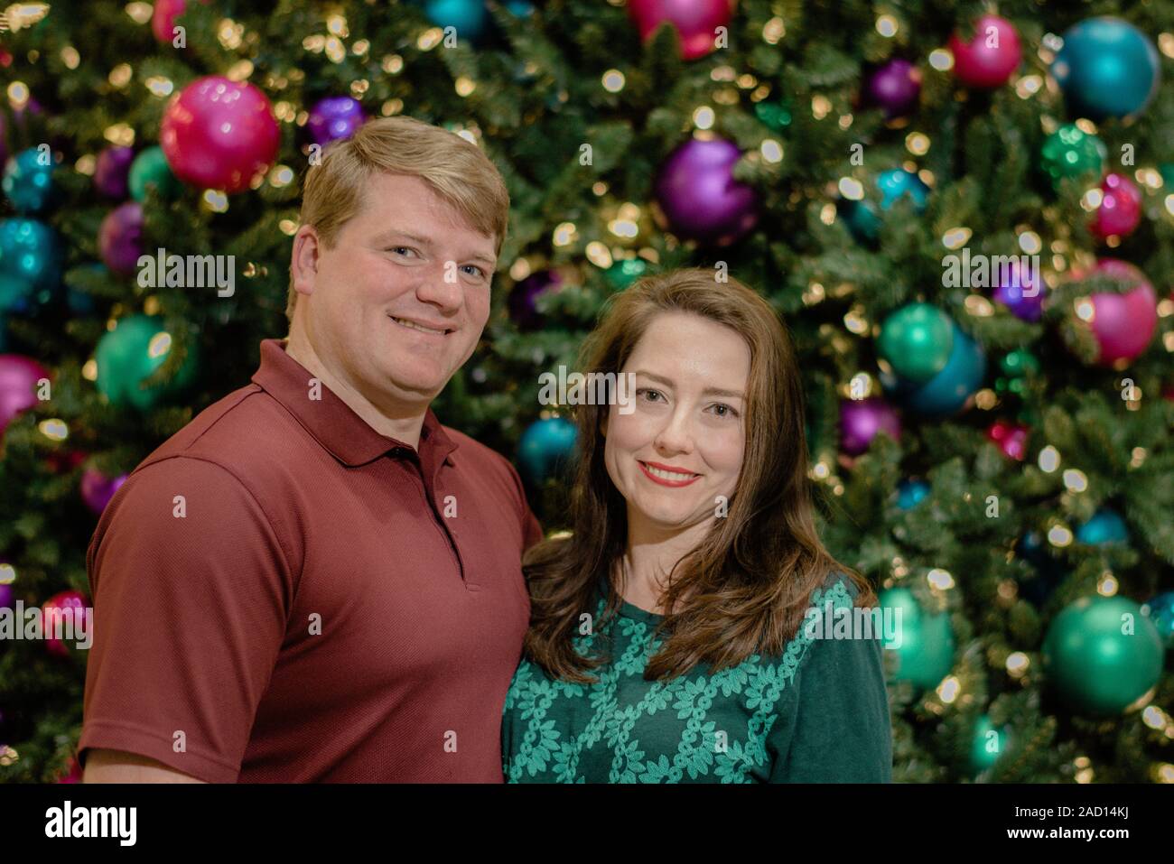 Paar vor einem geschmückten Weihnachtsbaum Stockfoto
