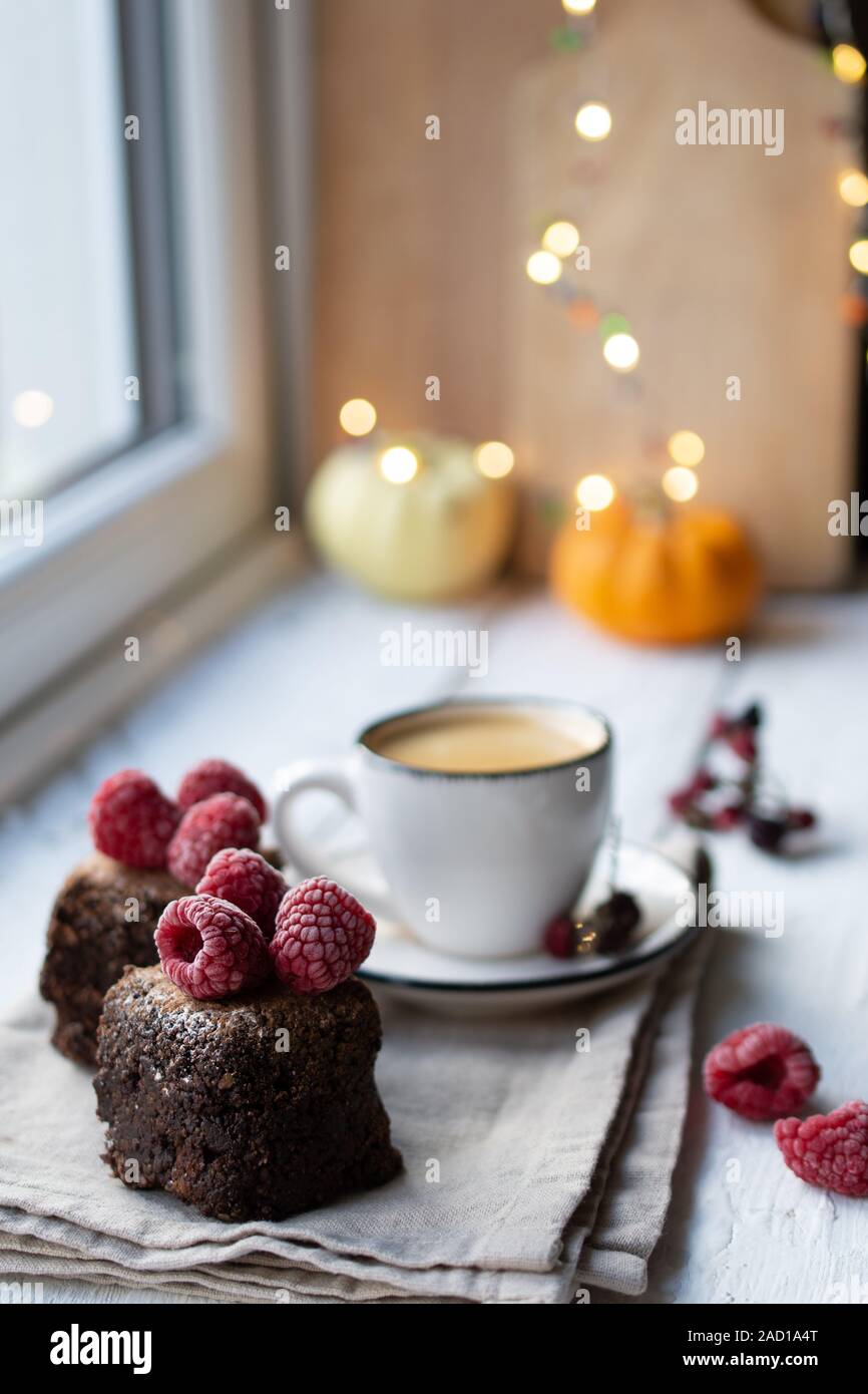 Dessert Schokolade auf der Fensterbank mit Himbeeren und leckeren Kaffee. Weihnachtsdekorationen. Gesundes Essen und Trinken Stockfoto