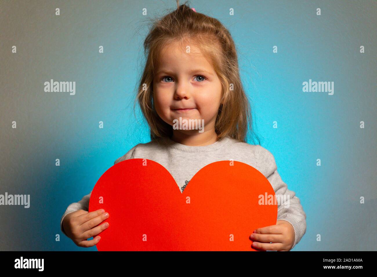Kleines Mädchen mit roten großen leeren Herzen in der Kamera auf der Suche Stockfoto