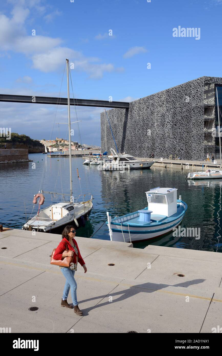 Einzelne Frauen oder junge Frau touristische Entlang Kai von Hafen mit Fischerbooten vor MUCEM Museum Marseille Provence Frankreich Stockfoto