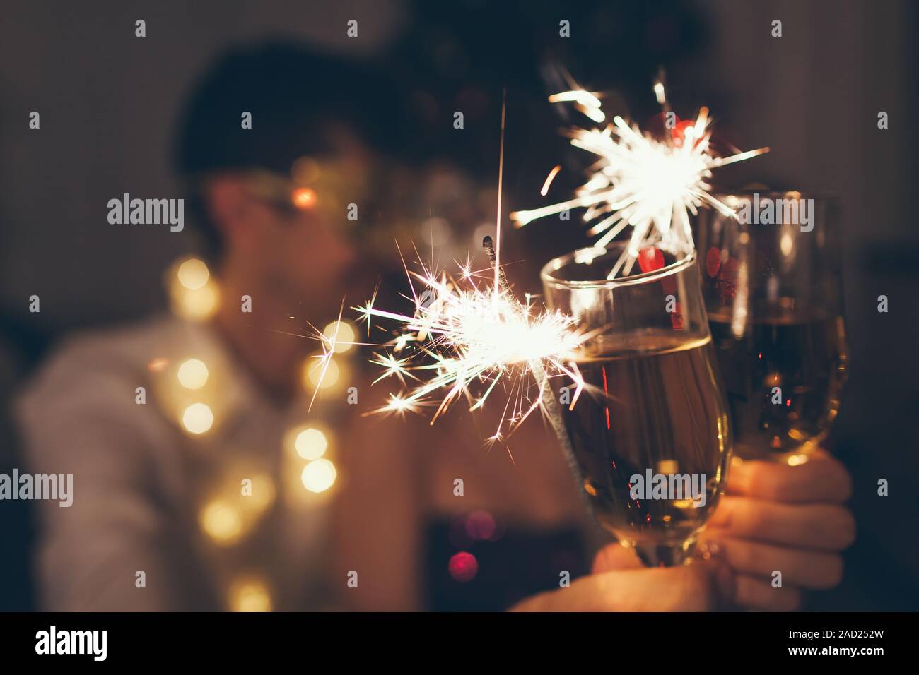 Weihnachten und Neujahr party Konzept. Verliebtes Paar brennende Wunderkerzen beleuchtete Weihnachtsbaum mit Champagner. Stockfoto