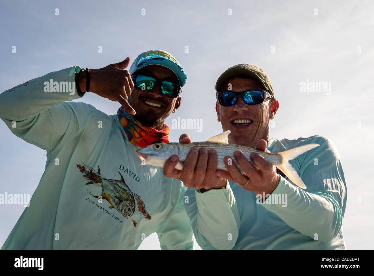 Ambergris Caye, Belize - November, 16, 2019. Aufgeregt Fliegenfischer mit Belizean Fishing Guide zeigt die bonefish, die er gerade in der Karibik gefangen Stockfoto