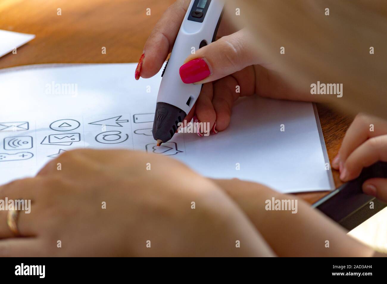 Mutter mit Kind Zeichnen auf einem weißen Blatt Papier mit 3D-pen. Close Up. Ansicht von oben von der Seite. Stockfoto