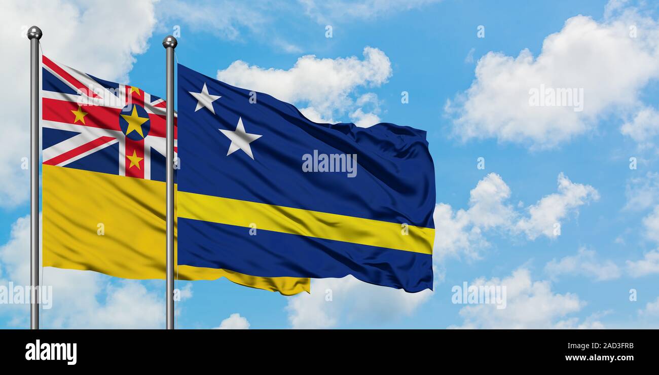 Niue und Curacao Flagge im Wind gegen Weiße bewölkt blauer Himmel zusammen. Diplomatie Konzept, internationale Beziehungen. Stockfoto