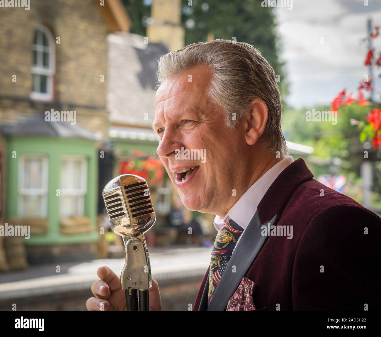 Nahaufnahme männlichen Vintage-Sänger / vierziger Crooner unterhaltsam Vintage-Bahnhof, Severn Valley Railway, Gesang Mund offen in Vintage-Mikrofon. Stockfoto