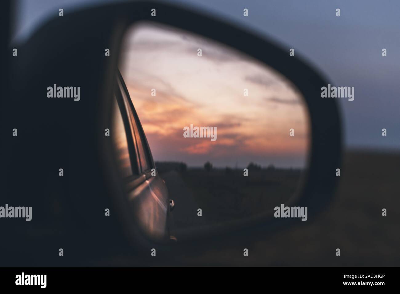 Rückspiegel eines Autos im Sonnenuntergang. Fahrzeug Außenspiegel mit Reflexion der Dämmerung Himmel und Wolken, selektive konzentrieren. Stockfoto