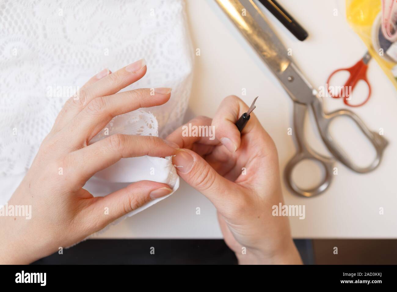 Mädchen unrips Gewebe in der Nähe von Nähmaschine Stockfoto