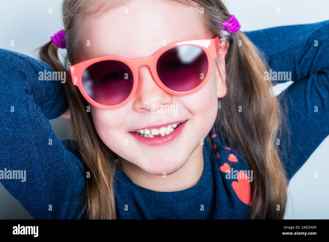 Freundlich lächelnde niedliche Kind mit Zähnen abgefallen - vorschüler Mädchen in der Sonnenbrille mit offenen Mund ohne Milch Zahn Stockfoto