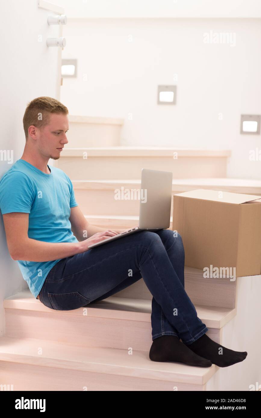 Junger Mann im Treppenhaus zu Hause sitzen Stockfoto