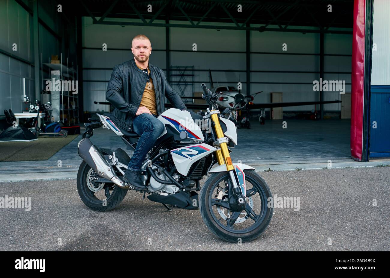 Mann auf dem Motorrad am Hangar mit dem Flugzeug Stockfoto