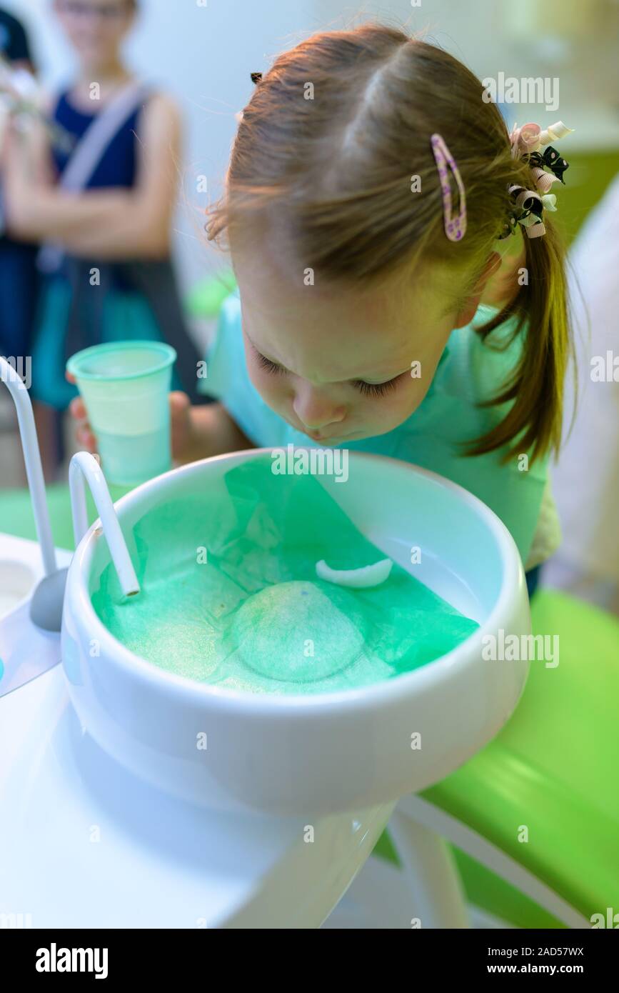 Am Zahnarzt zahnmedizinische Patienten Mädchen Wasser spuckt nach Behandlung - kleines Mädchen sass im Zahnarztbüro Stockfoto