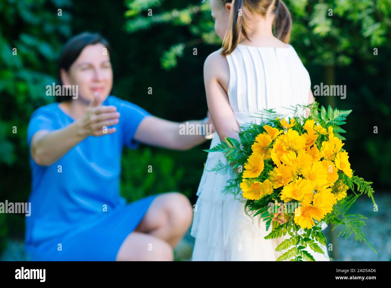 Happy Mother's Day! Kind Mädchen gratuliert Mama und gibt ihr Bukett von gelben Blumen - sehr geringe Tiefenschärfe (Fokus auf Stockfoto