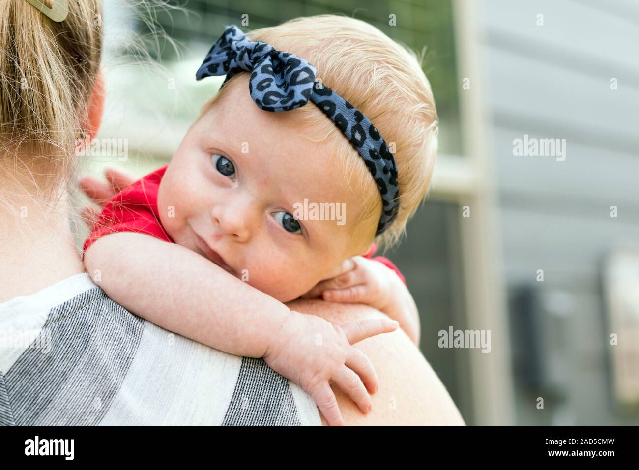 Mutter Holding Happy Baby mit hellen blauen Augen Stockfoto