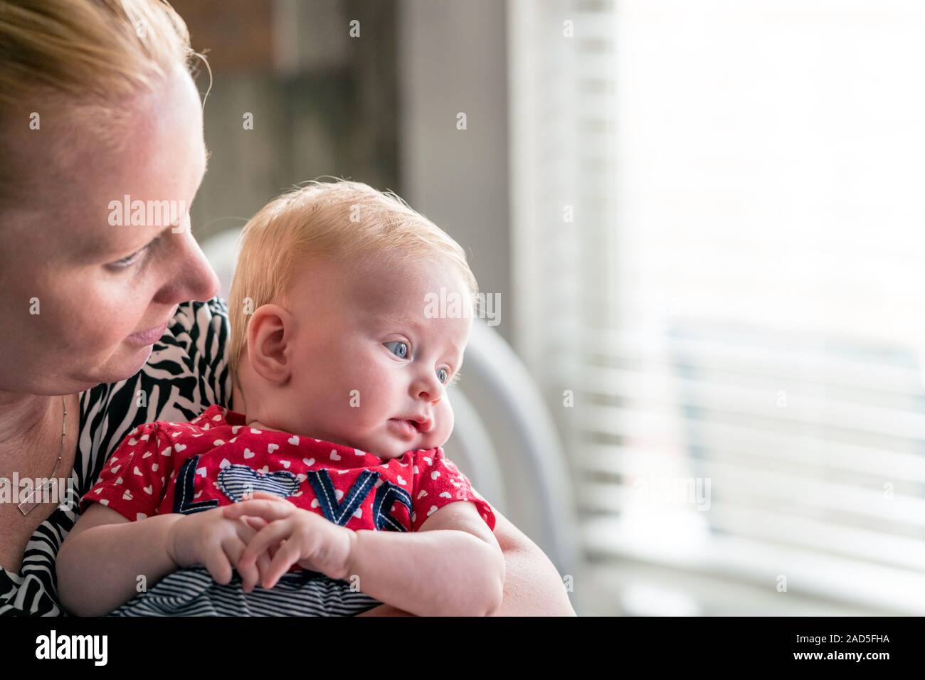 Mutter Holding Happy Baby mit hellen blauen Augen Stockfoto