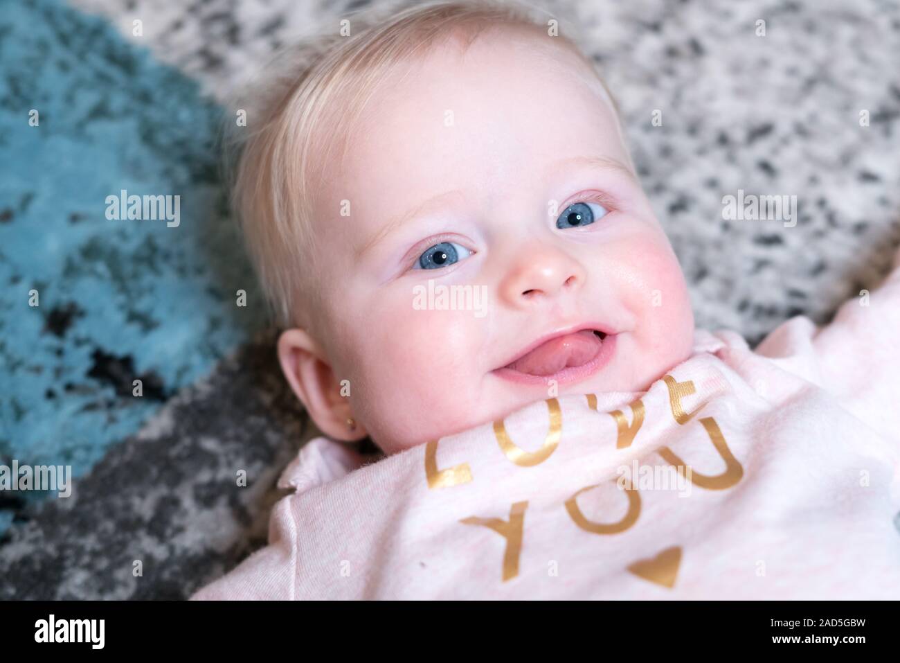 Glücklich lächelnde Baby mit blauen Augen - Alter 6 Monate Stockfoto