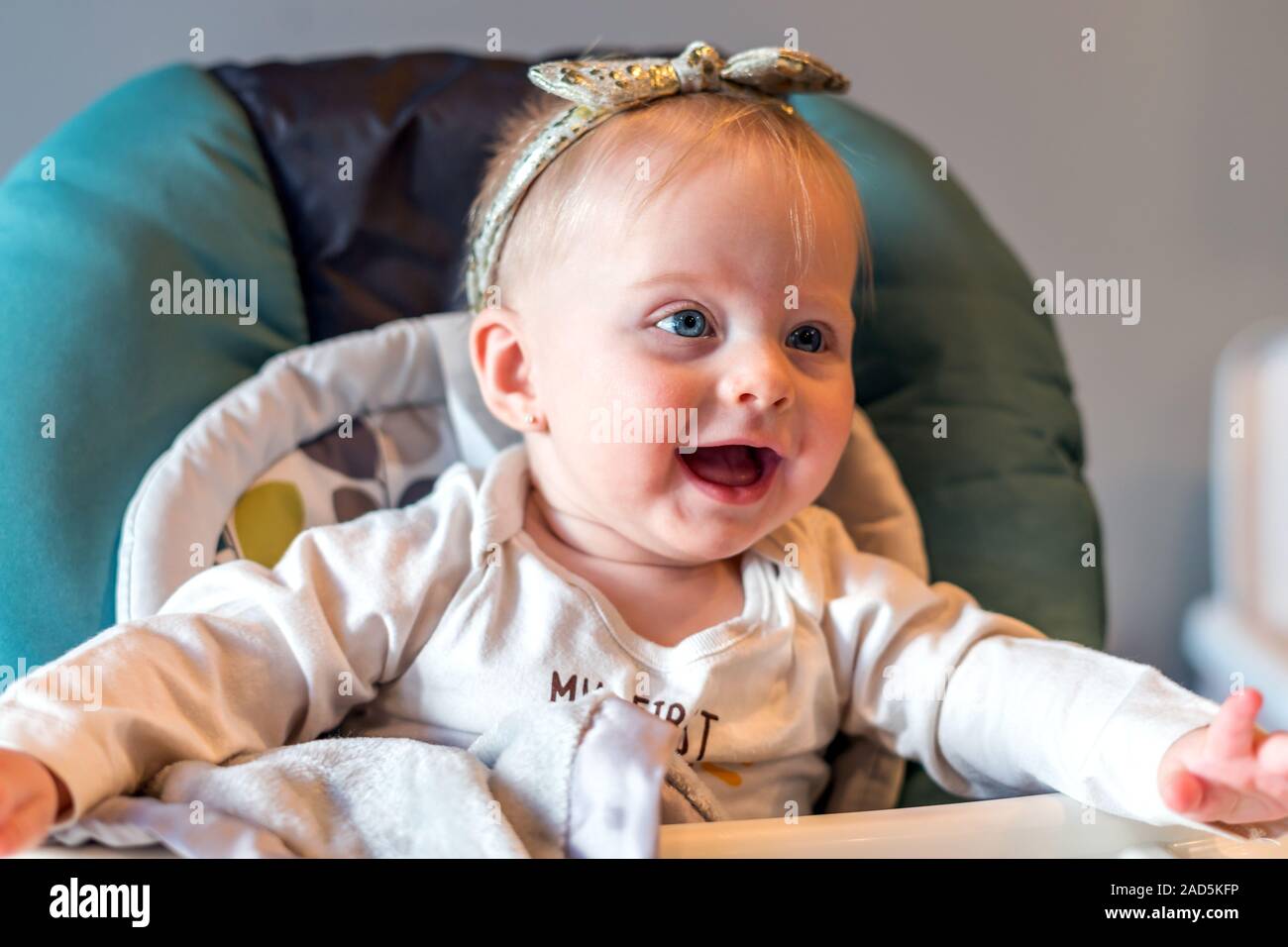 Baby Mädchen glücklich und lächelnd auf hohen Stuhl - Alter 6 Monate Stockfoto