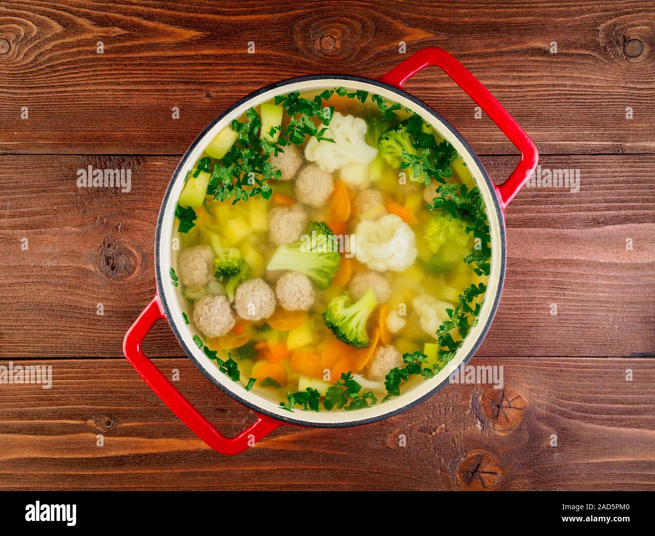 Große Metal cast rot Pan mit köstlichen heißen Suppe mit Gemüse und Frikadellen, Blumenkohl, Brokkoli, Möhren, Paprika, Kartoffeln, gesunde Diät essen. Br Stockfoto