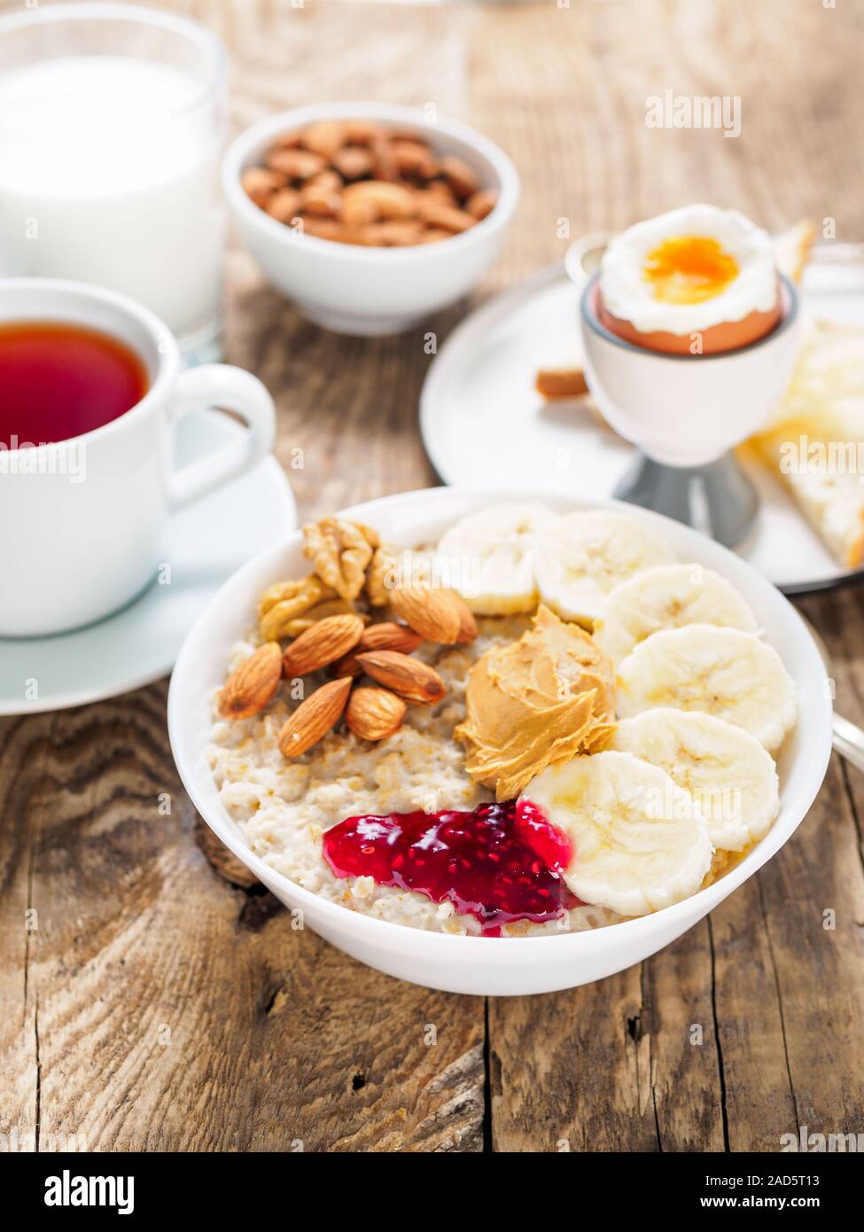 Haferflocken mit Muttern und Marmelade, weich gekochte Eier, selektiver Fokus, Seitenansicht, vertikale Rahmen Stockfoto