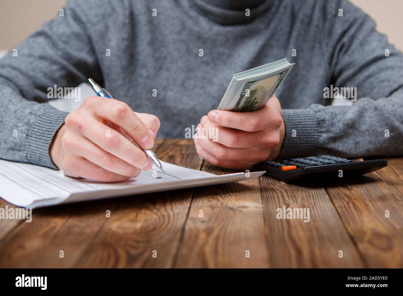 Kaukasische Hände zählen-Dollar-Banknoten auf dunklen Holztisch Stockfoto