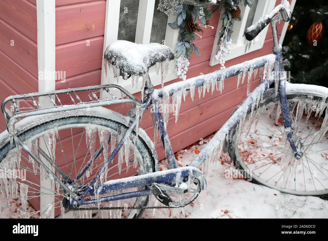 Das eisige Wetter und Vereisung, gefroren Fahrrad in Eiszapfen an Weihnachtsdekorationen Hintergrund auf einer winter Straße geparkt abgedeckt Stockfoto