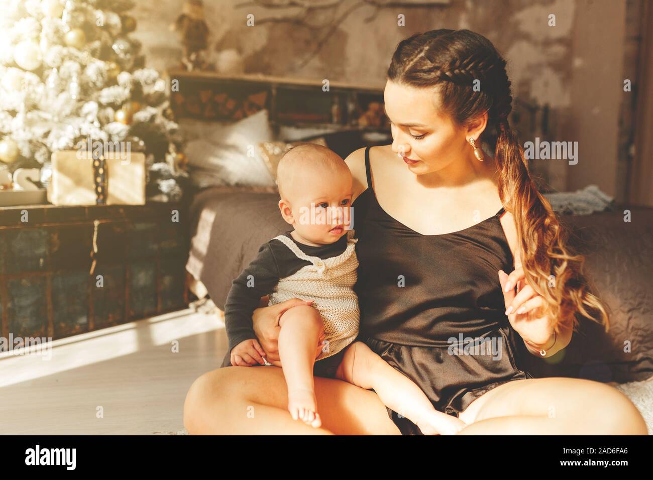 Lächelnde Mutter spielt mit schönen Baby in der Nähe von Weihnachten Baum Stockfoto