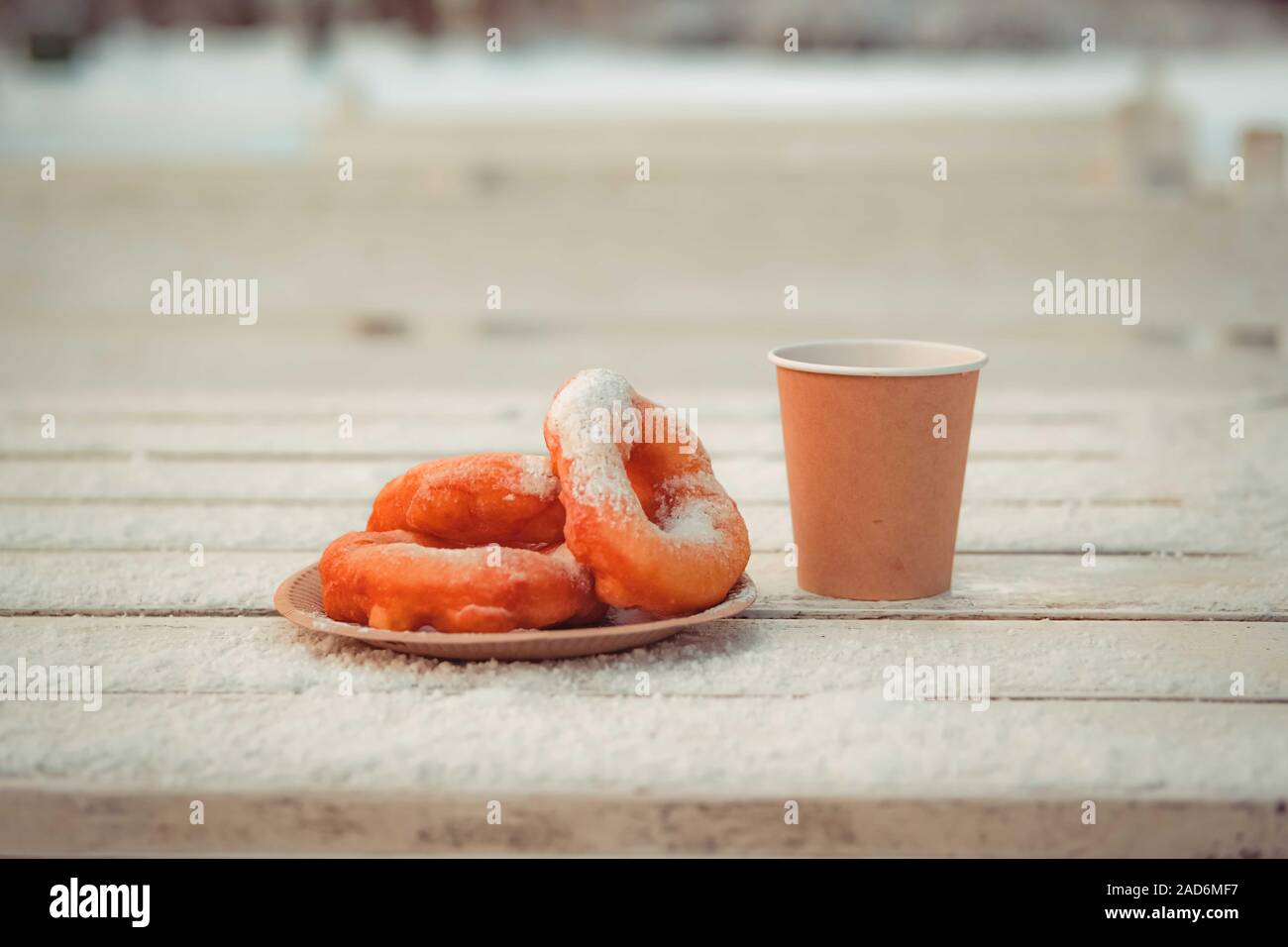 Russische fast food Bagel pyshki und Papier Tasse mit Tee oder Kaffee auf hölzernen Tisch, bedeckt mit Schnee, Winter Snack im Park. Stockfoto