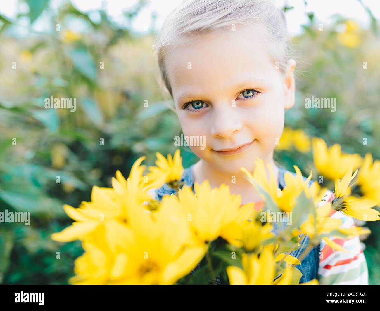 Kleines Mädchen mit einem Strauß gelber Wildblumen in einer Wiese Stockfoto