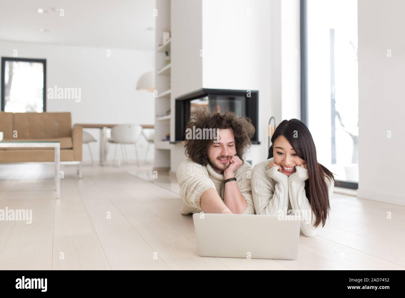 Jungen multiethnischen Paar mit einem Laptop auf dem Boden Stockfoto