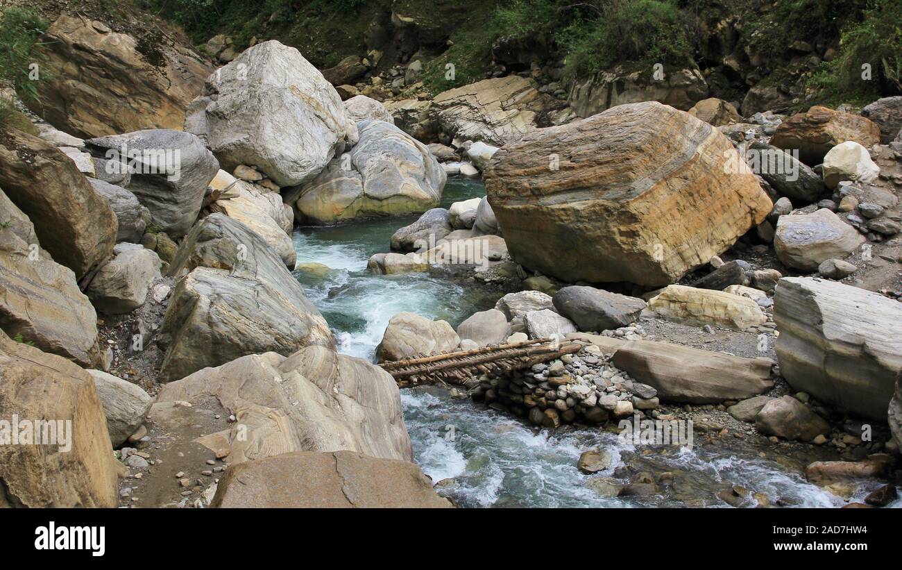 Kimrong Khola, Fluss in der Nähe von Ghandruk, Nepal. Holzbrücke und Big Boulder. Stockfoto