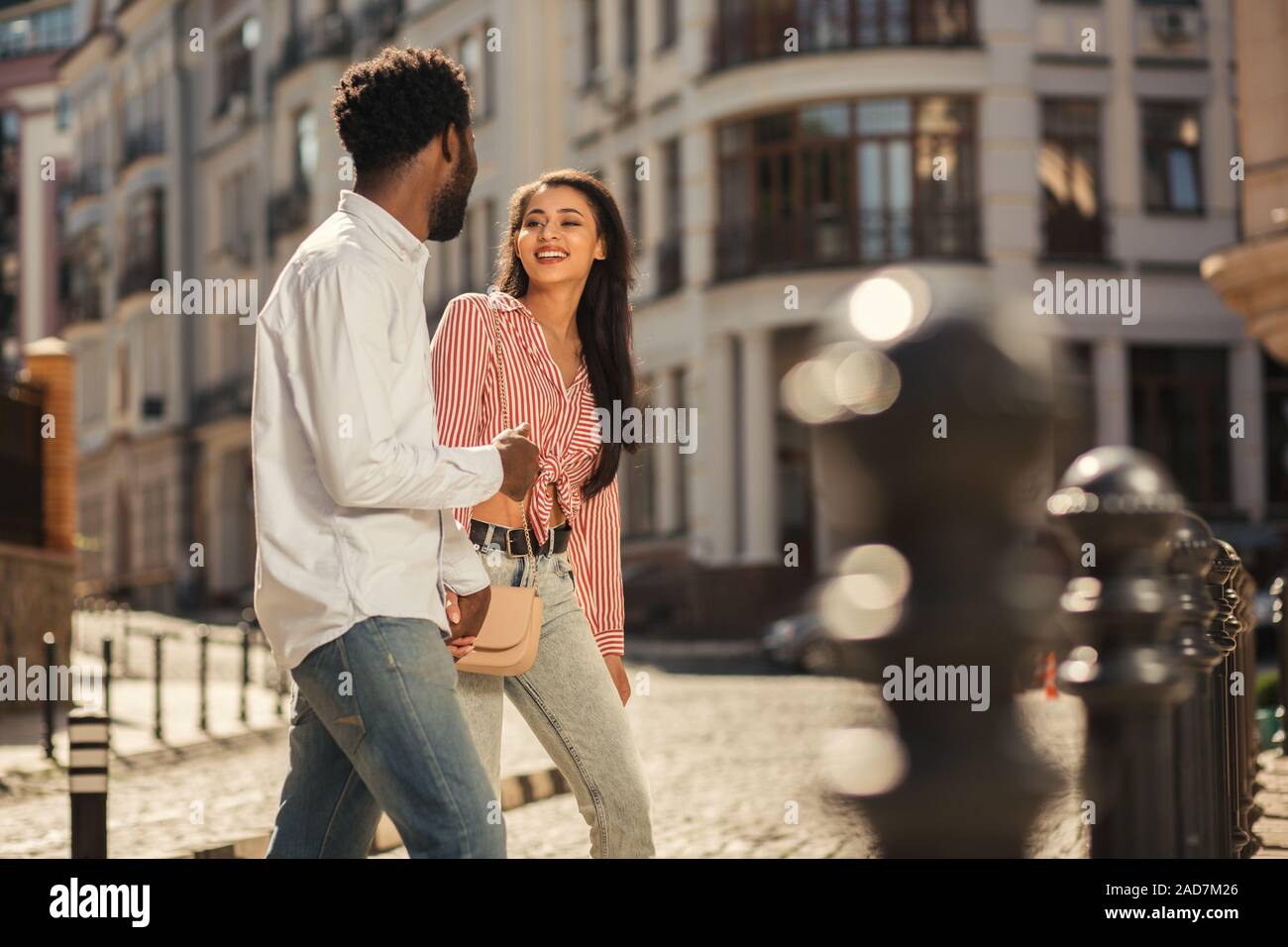 Junger Mann und Frau halten sich an den Händen, während die Straße überqueren Stockfoto