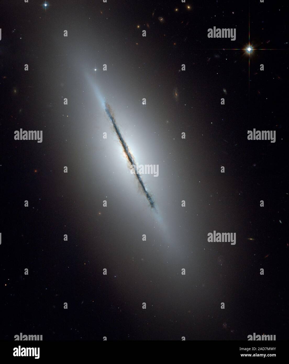 Dies ist ein einzigartiges NASA-Hubble-Weltraumteleskop Blick auf die Galaxie NGC 5866 gekippt fast Kante zu unserer Sichtlinie. Scharfe Hubbles Vision offenbart eine scharfe Staubband Division der Galaxie in zwei Hälften. Das Bild zeigt die Struktur der Galaxie: Eine subtile, rötlich Ausbuchtung, die einen hellen Kern, eine blaue Scheibe der Sterne, die parallel zu den Staub weg läuft, und eine transparente äußere Halo. Einige schwache, wispy Spuren von Staub kann gesehen werden weg von der Scheibe der Galaxie, die sich in der Ausbuchtung und inneren Halo der Galaxie. Der äußere Halo ist übersät mit zahlreichen gravitativ gebundenen Clus Stockfoto