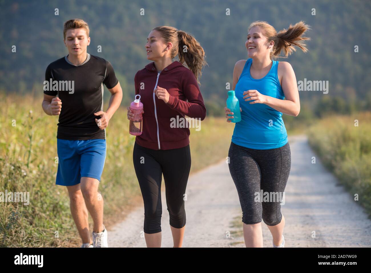 Junge Leute joggen auf Landstraße Stockfoto