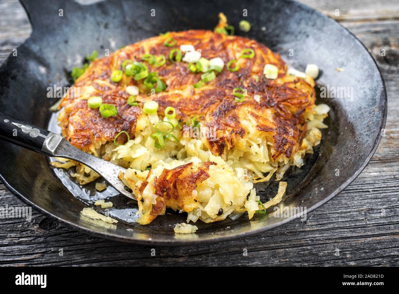 Traditionelle Schweizer Rösti als Beilage mit Lauch als closeup in einer Pfanne Stockfoto