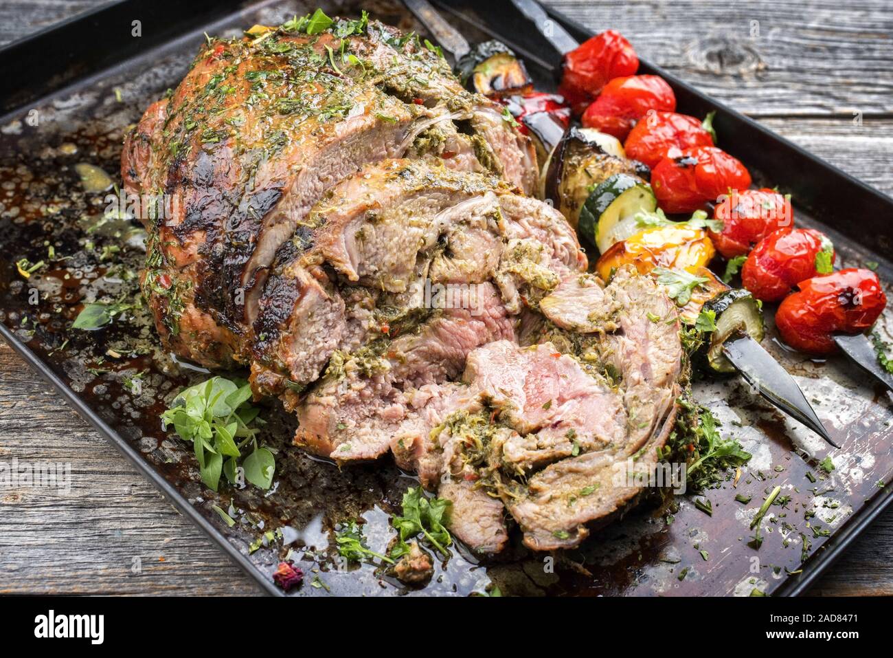 Traditionelle Lammkeule mit Gemüse Spieß als Closeup auf ein Blech geschnitten Stockfoto