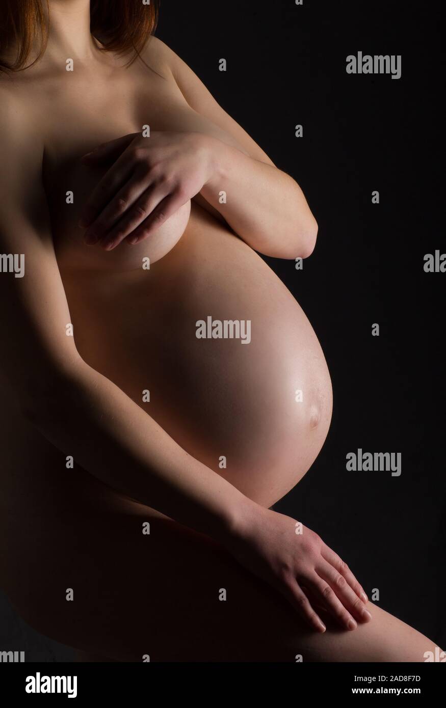 Schwangere, werdende Mutter auf schwarzem Hintergrund, Stockfoto