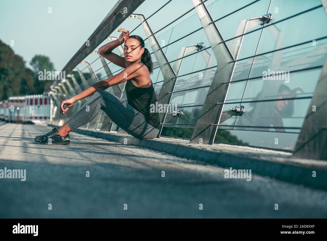 Müde Sportlerin im Glas Geländer Foto sitzen Stockfoto