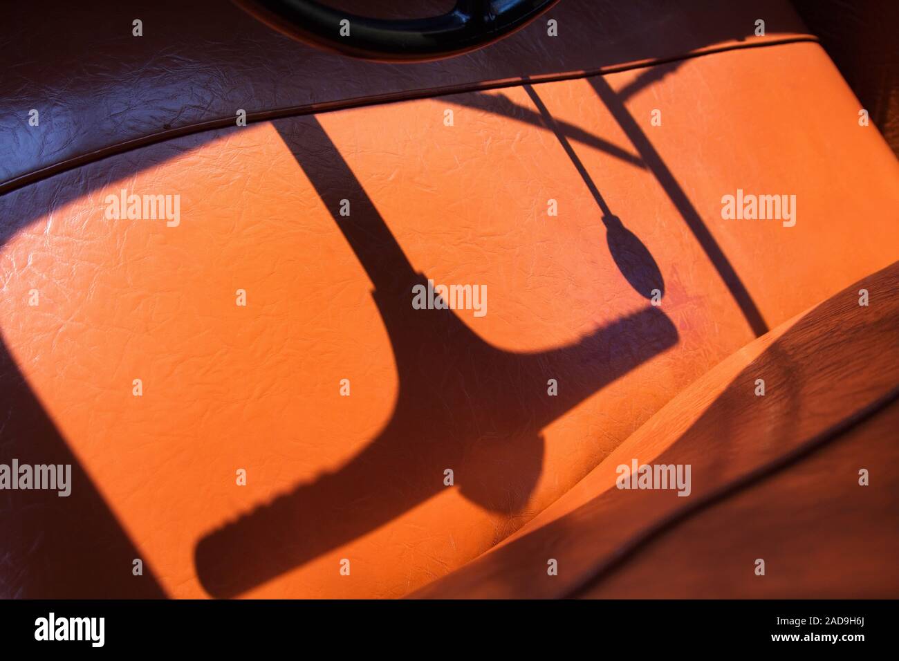 Ein Lenkrad und Schalthebel Schatten auf vinyl Sitzbänke im Inneren ein Klassiker und Oldtimer Limousine. Stockfoto